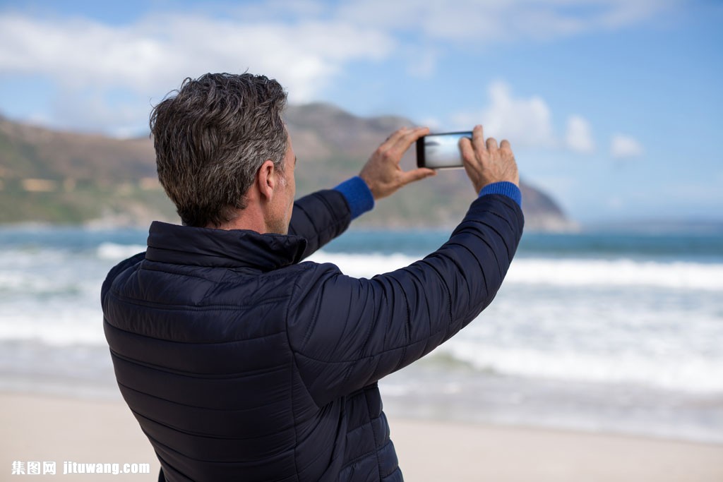 海边拿手机拍照人男人